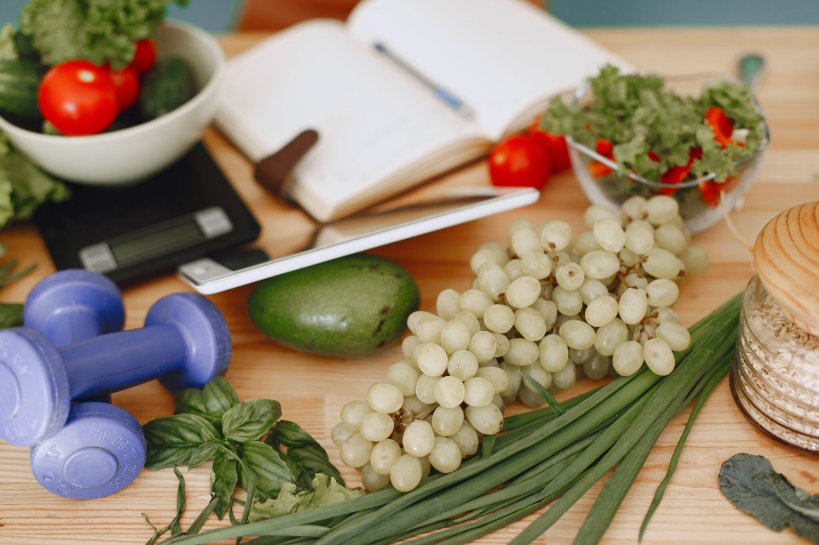 Fresh vegetables, fruit, oats, dumbbells and a planner on a wooden table